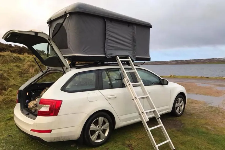 Rooftop tent on a white car beside the water